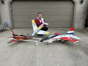 A man sitting on the ground with two planes.