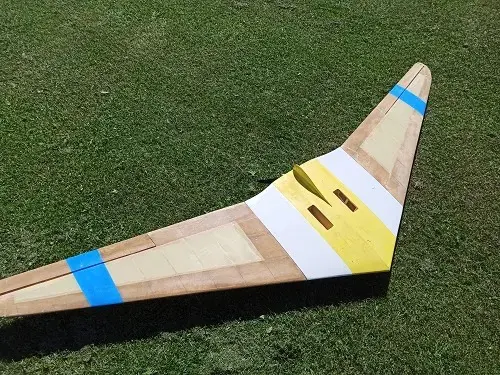 A wooden airplane sitting on top of a green field.