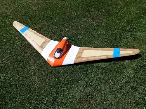A small orange and white plane sitting on top of grass.