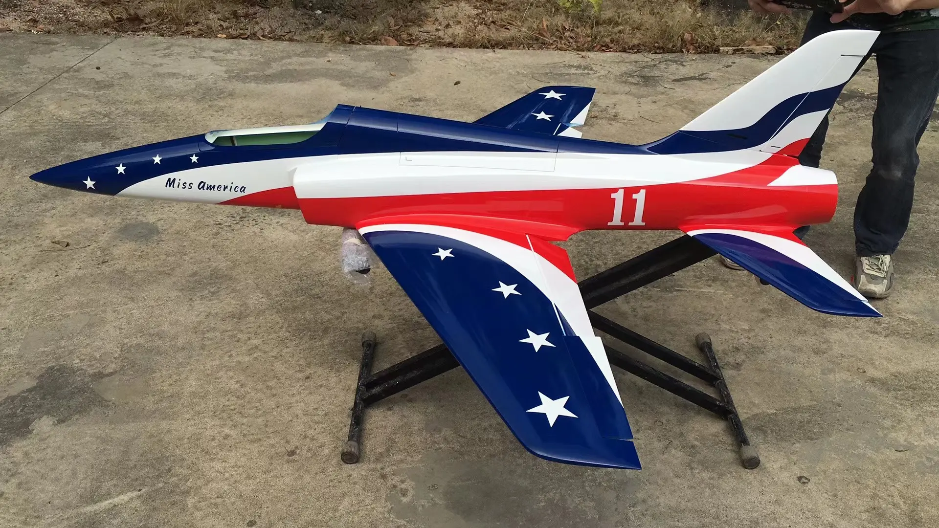 A red white and blue jet sitting on top of a stand.