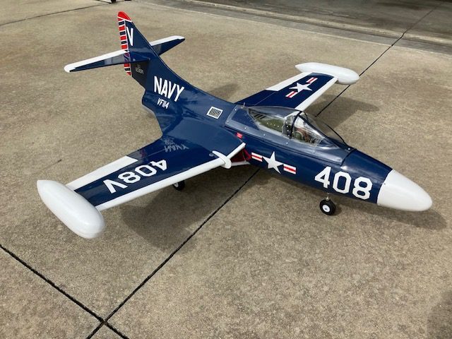 A navy fighter jet sitting on top of concrete.