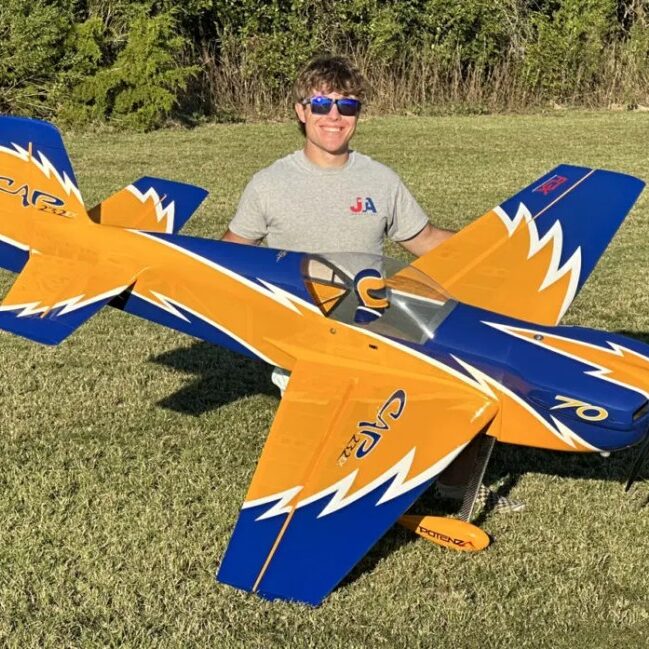 A man standing next to an airplane in the grass.