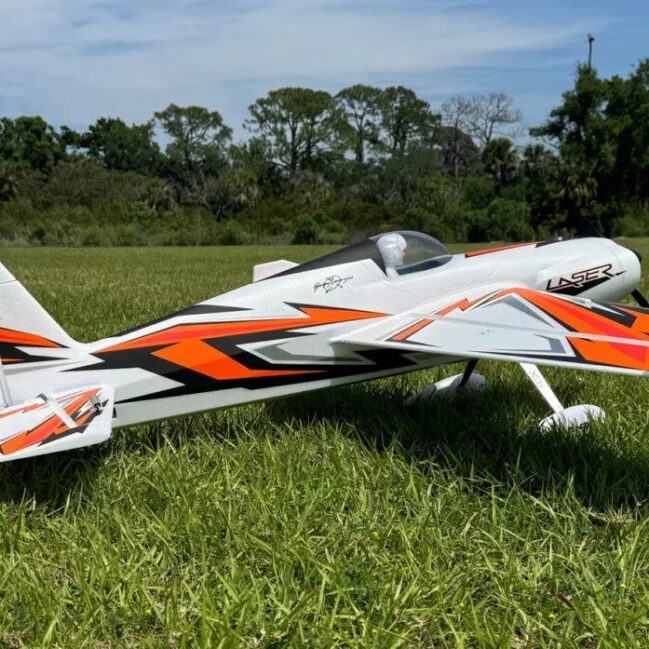 A small white and orange plane sitting in the grass.