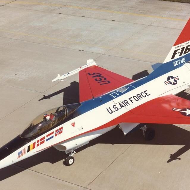 A red, white and blue jet fighter sitting on top of an airport runway.