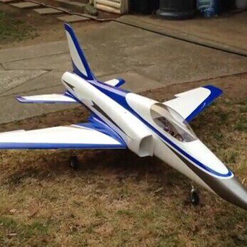 A blue and white jet plane sitting on top of grass.